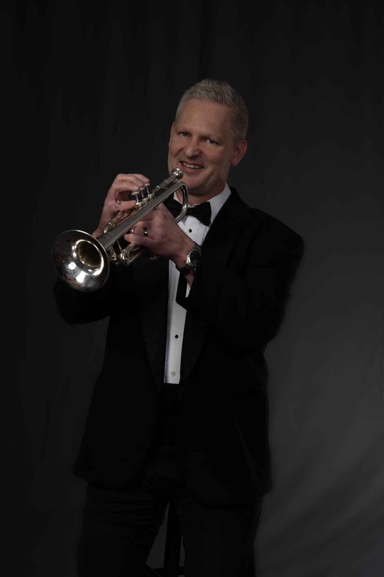 Christopher Wilson performing on trumpet in concert dress, smiling at the audience